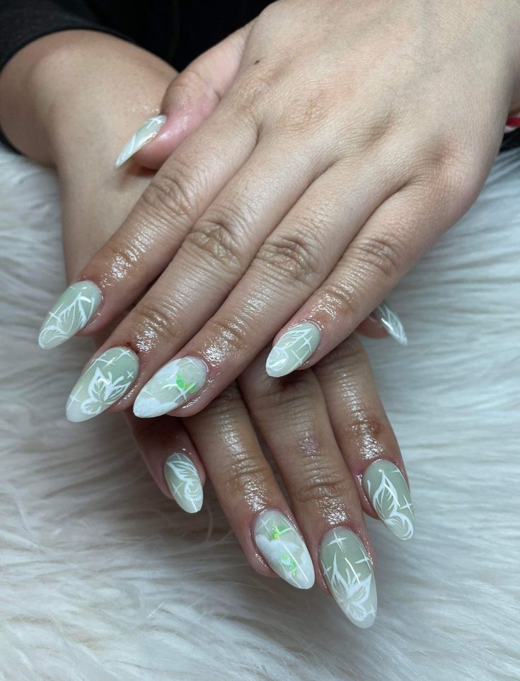 Elegant Almond-Shaped Nail Art: Soft White and Light Green Floral Designs on Clear Base.