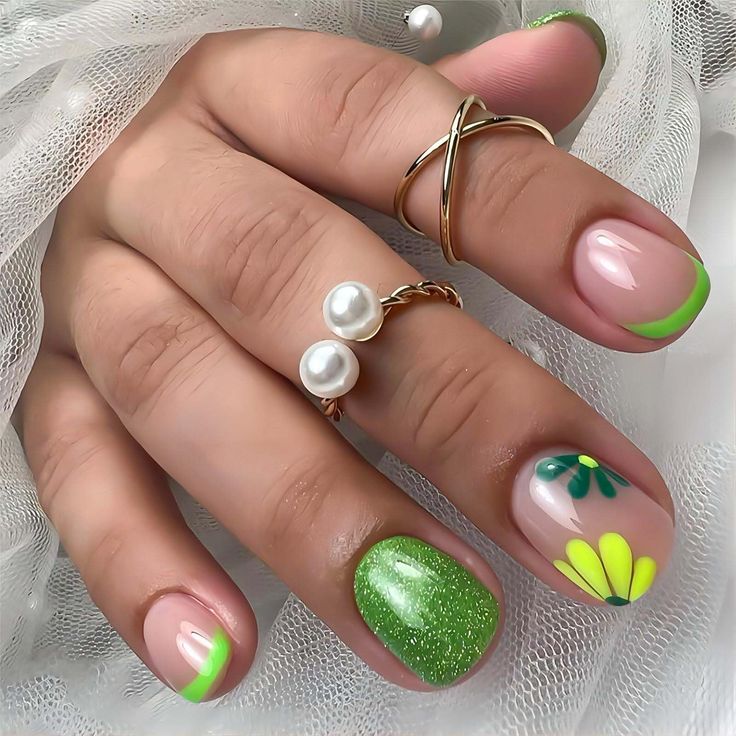 Chic Vibrant Nail Design with Floral Patterns and Glamorous Green Accents.