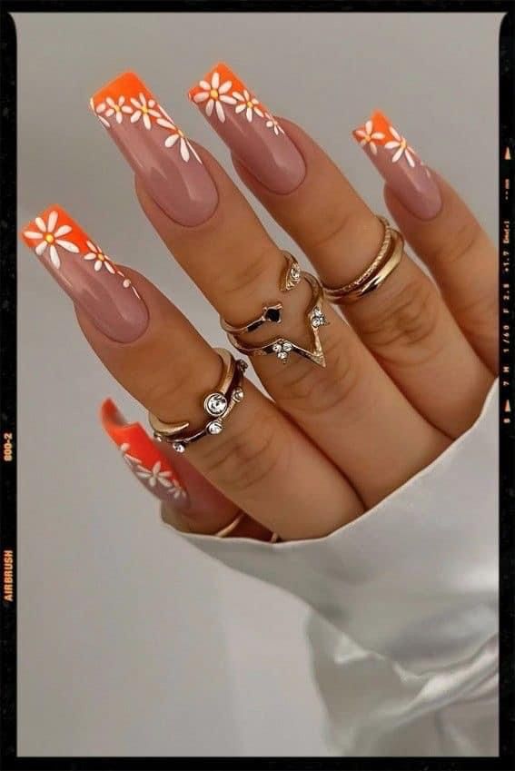 Vibrant Gradient Nail Design with Delicate Floral Accents and Stylish Rings.