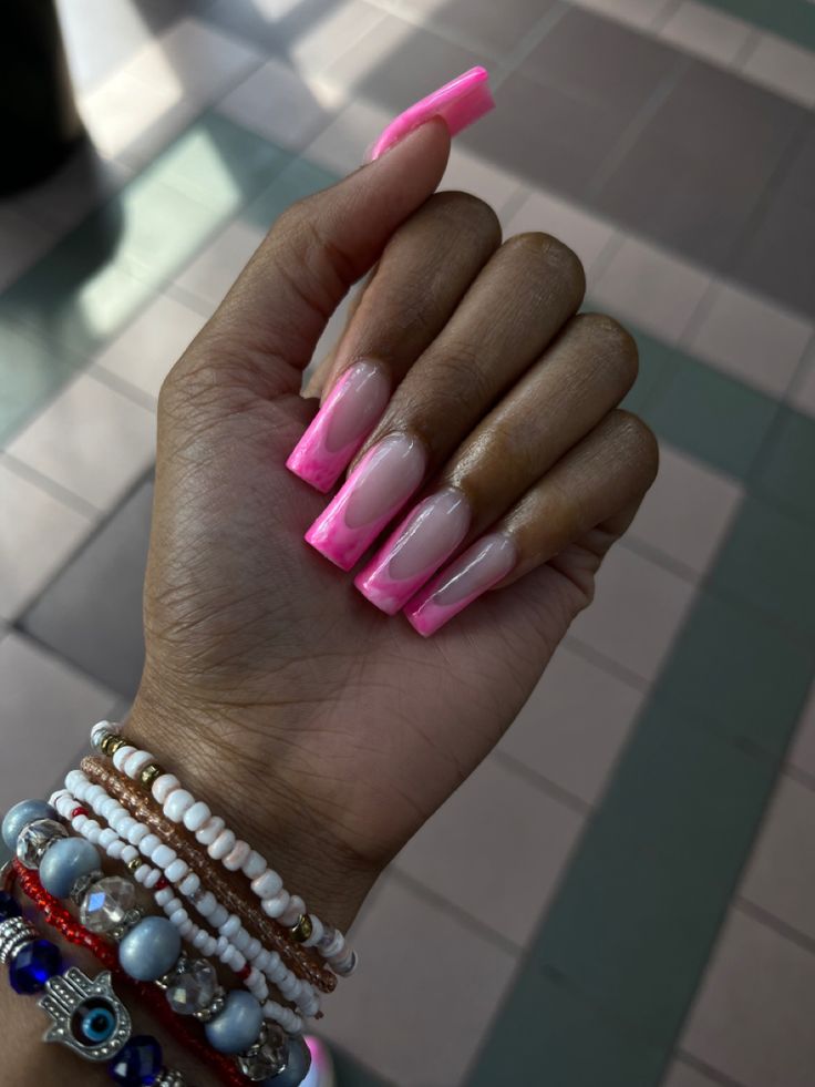 Bold Neon Pink-Tipped Acrylic Nails Paired with Colorful Bracelets for a Trendy Look.