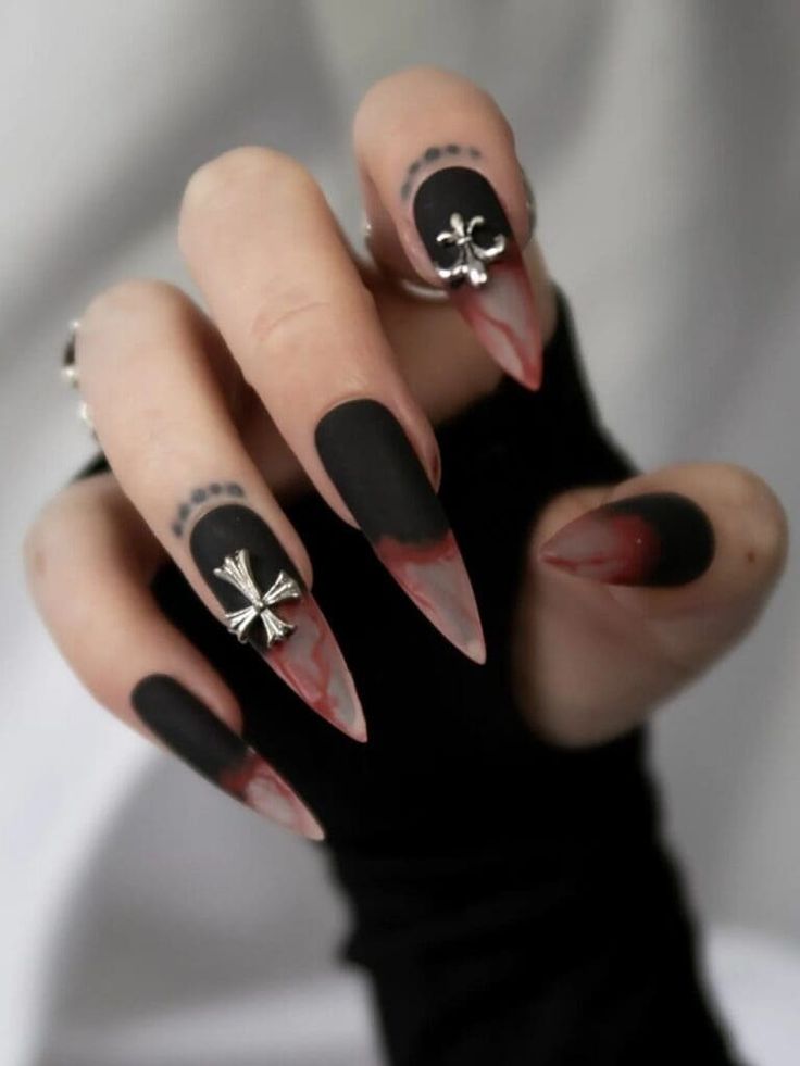 Edgy Stiletto Nail Design: Matte Black and Gradient Crimson Tips with Metallic Cross Accents.