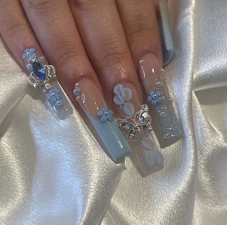 Elegant Delicate Blue Nail Design with Floral Embellishments and Sparkling Jewels.