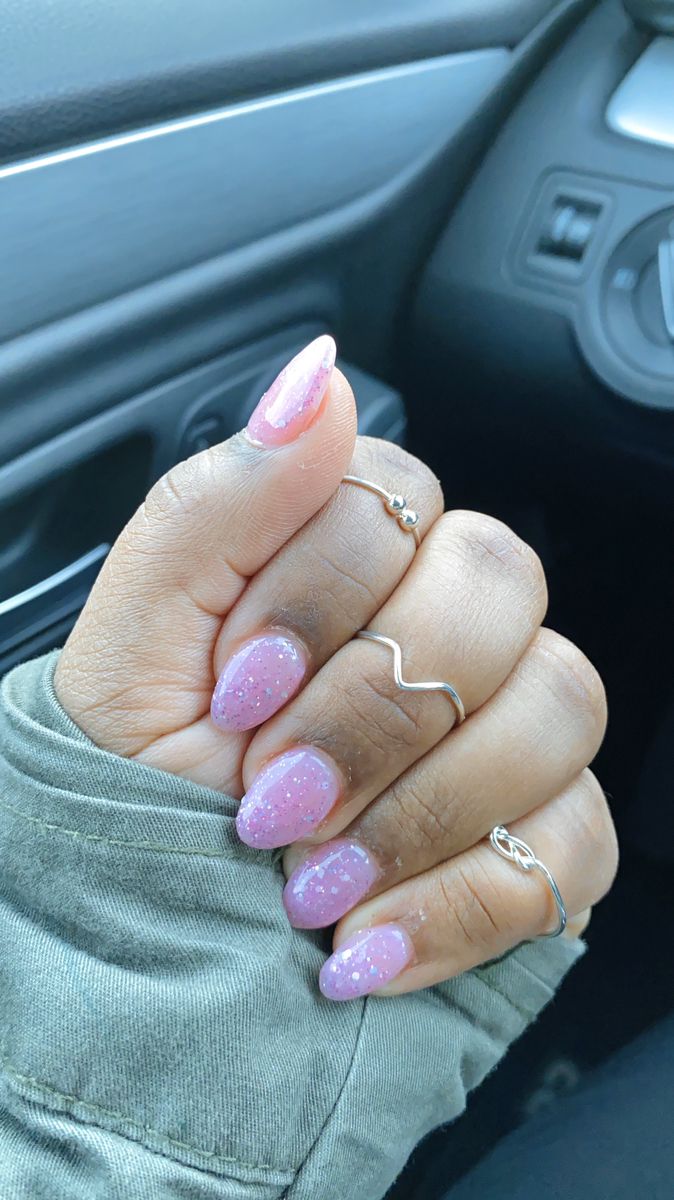 Elegant Glittery Pink Ombre Nails Paired with Minimalist Rings for a Playful Look.