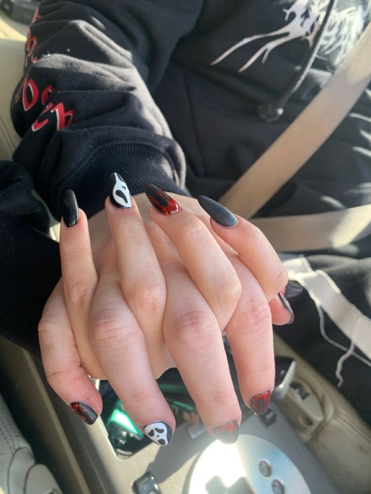 Bold Black and Red Nail Art: Edgy Designs with Ghostly Motifs and Glossy Finishes.