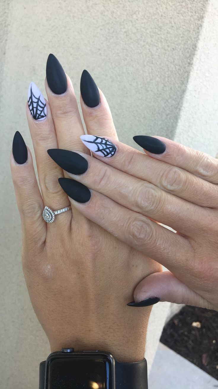 Chic Halloween Nail Design: Matte Black and Glossy White with Spider Web Patterns on Almond Tips.