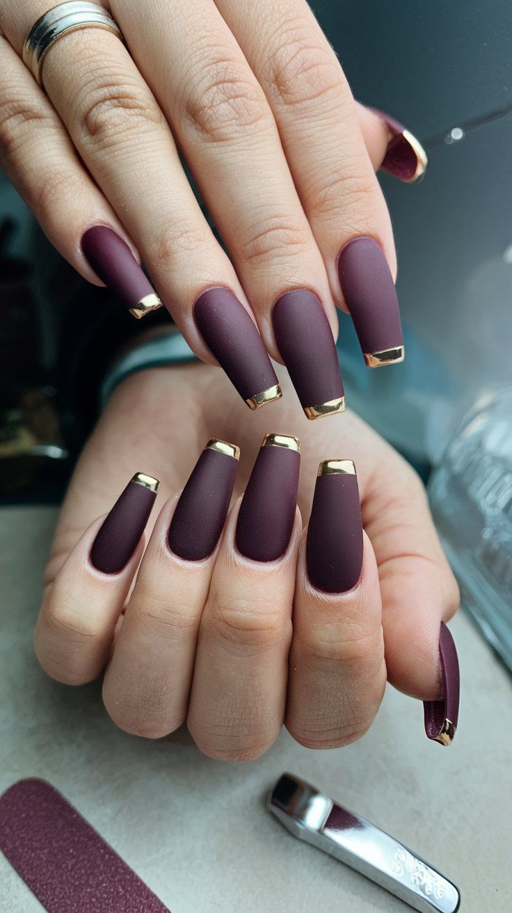 Sophisticated Matte Burgundy Nails with Striking Gold Tips for Every Occasion.