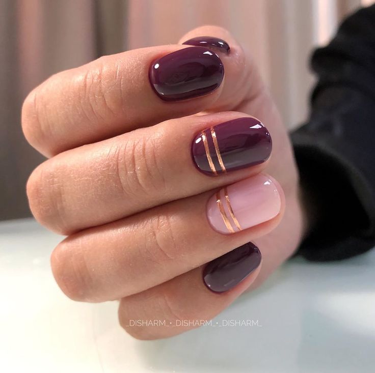 Chic Deep Plum and Nude Pink Nail Design with Sophisticated Gold Stripes.