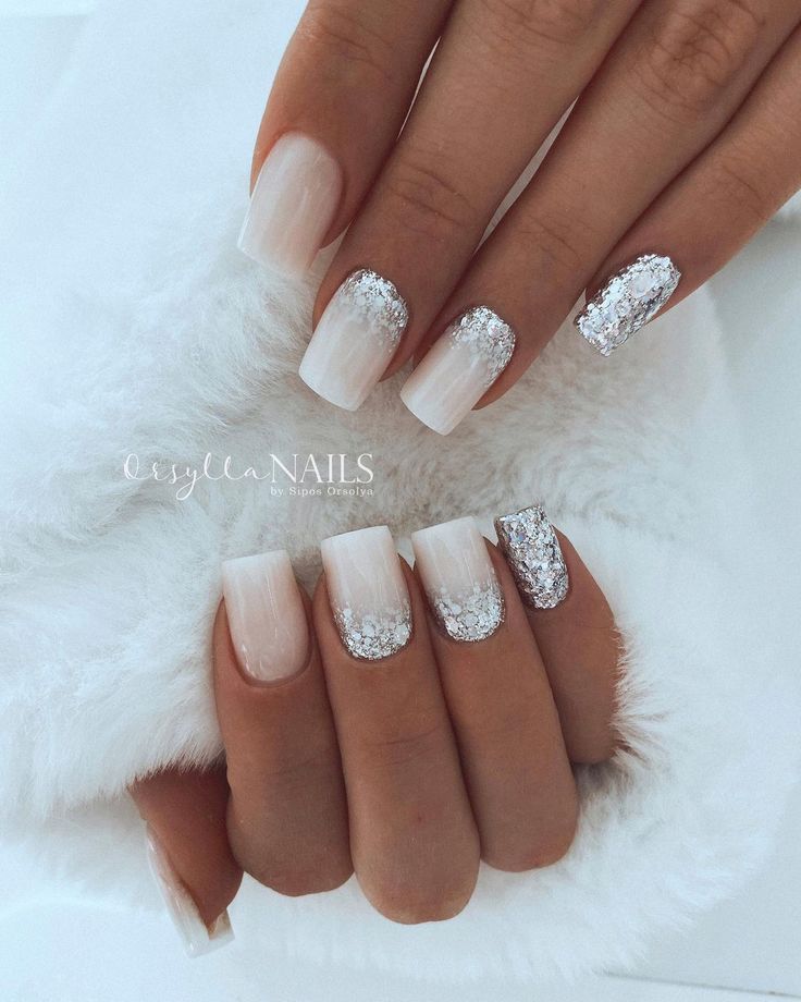 Chic Ombre Nail Design with Sheer Nude, White Tones, and Sparkling Glitter Accents.