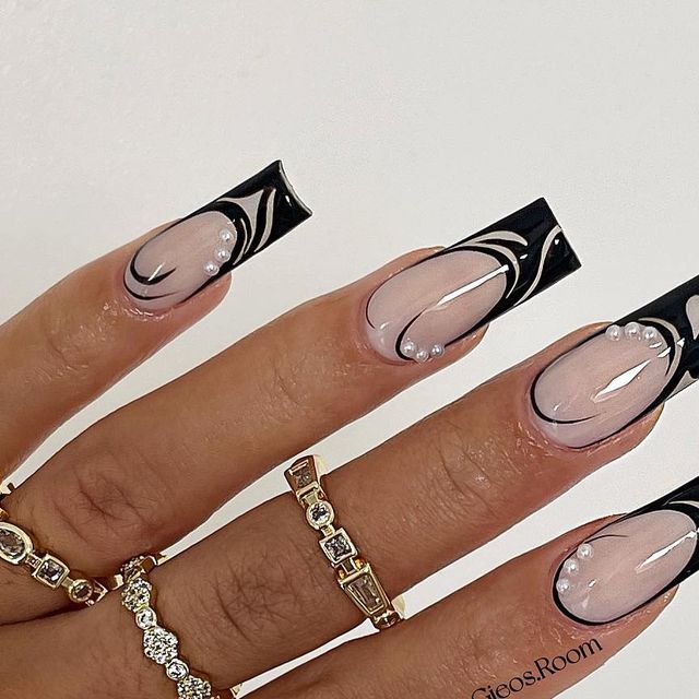 Chic Nude and Glossy Black Nail Design with Intricate Swirls and Embellishments.