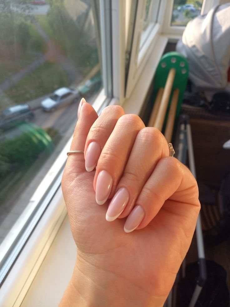 Elegant Almond-Shaped Nails with Soft Nude Polish and Subtle French Tips for a Chic Look.