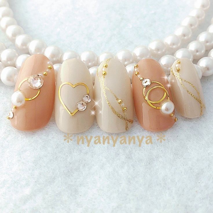 Elegant Nude and Cream Nail Design with Gold Accents and Glamorous Embellishments.