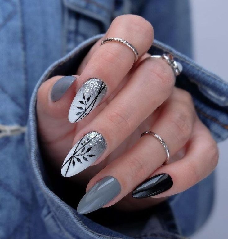 Elegant Black, White, and Gray Nail Design with Leaf Patterns and Glitter Accents.