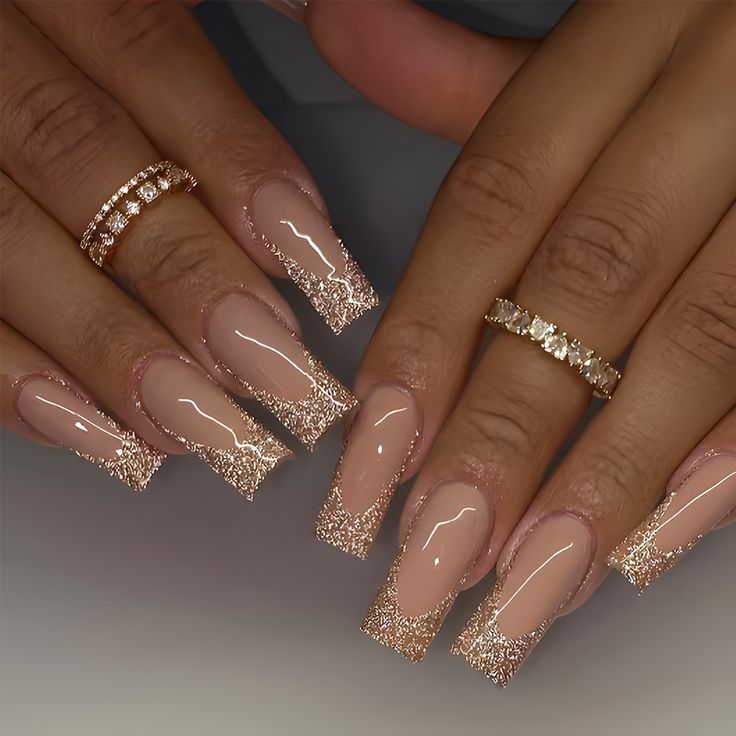 Sophisticated Nude Nail Design with Glitter Tips and Gold Accents.