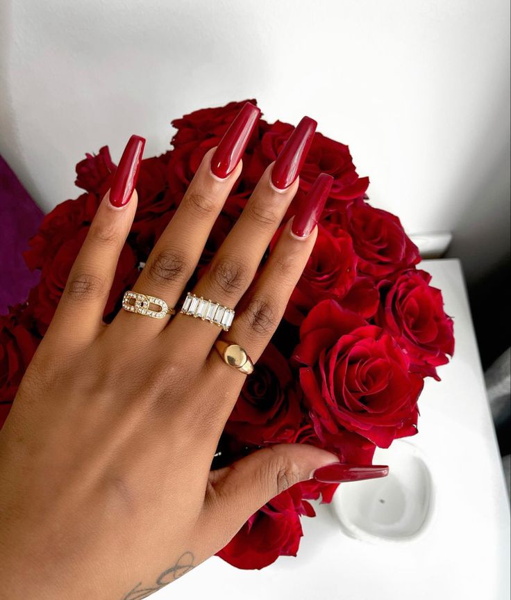 Glamorous Red Nails Complimenting a Lush Bouquet of Roses.