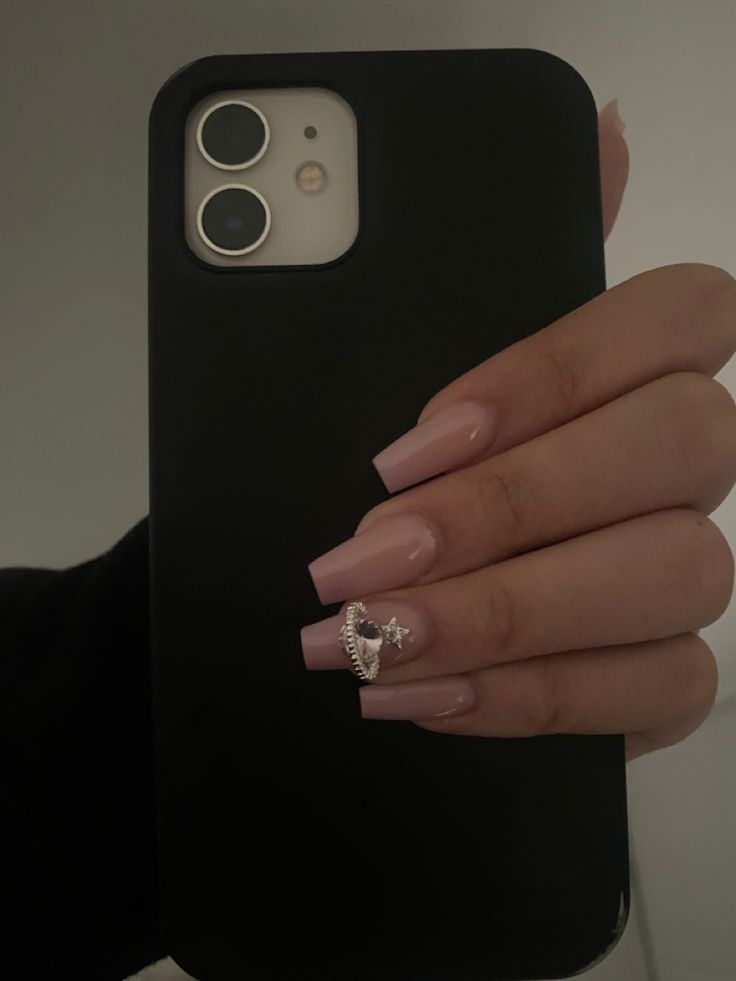 Chic Pastel Pink Nails with Glamorous Silver Crown Embellishment Enhance Stylish Smartphone Aesthetic.