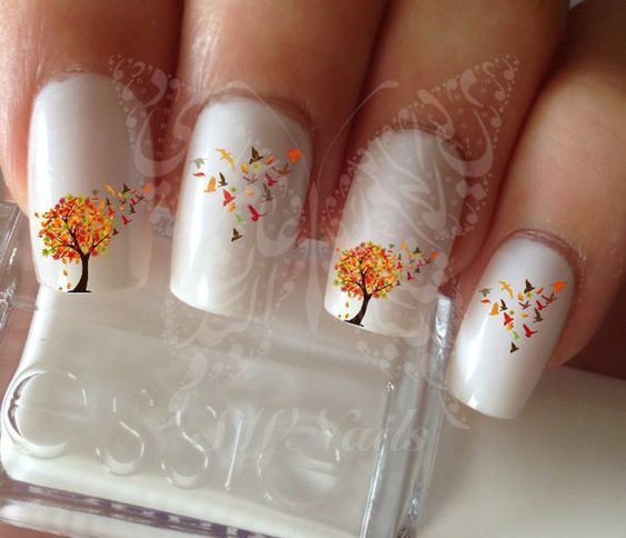 Whimsical Autumn Nail Art with Vibrant Trees and Fluttering Butterflies on Soft White Background.