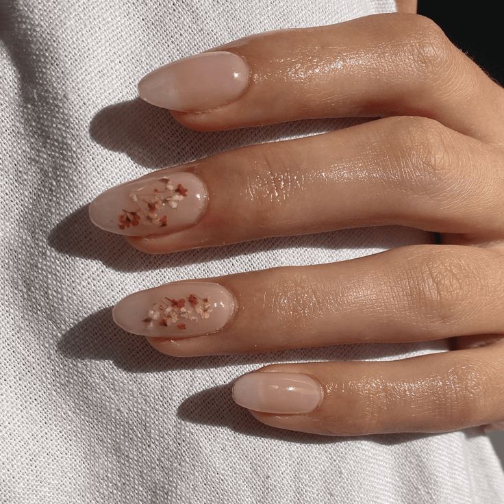 Elegant Nude Nail Design with Floral Accents and Subtle Shimmer