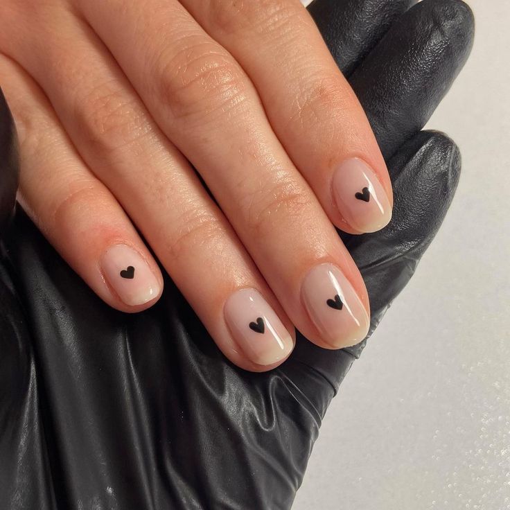 Chic Minimalist Nail Design with Nude Base and Playful Black Heart Accents.