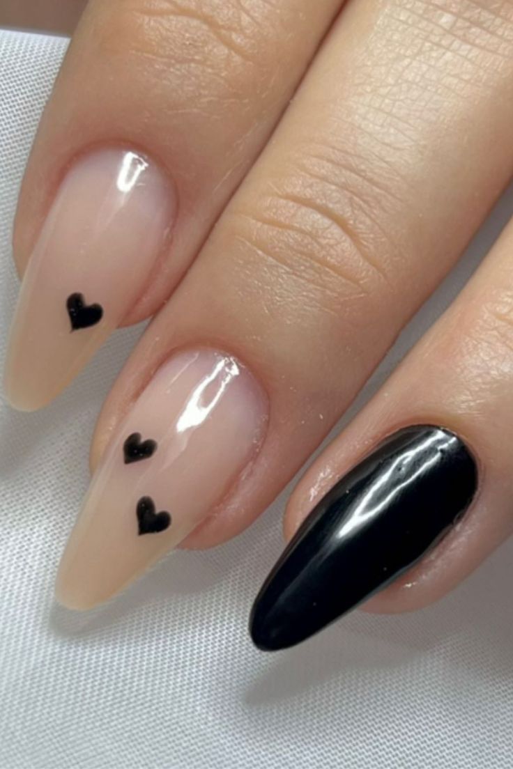 Chic Playful Elegance: Nude Nails with Black Heart Accents and Solid Black Polish.