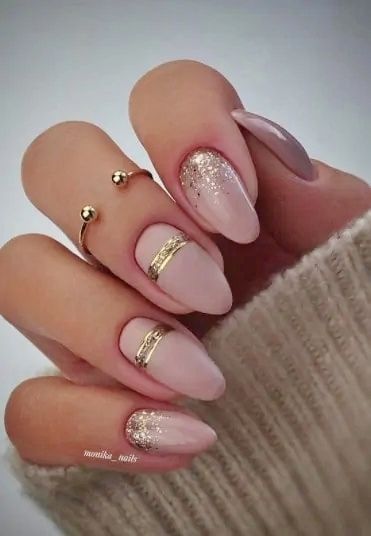 Chic and Sophisticated Nude Nail Design with Glitter Accents and Gold Rings