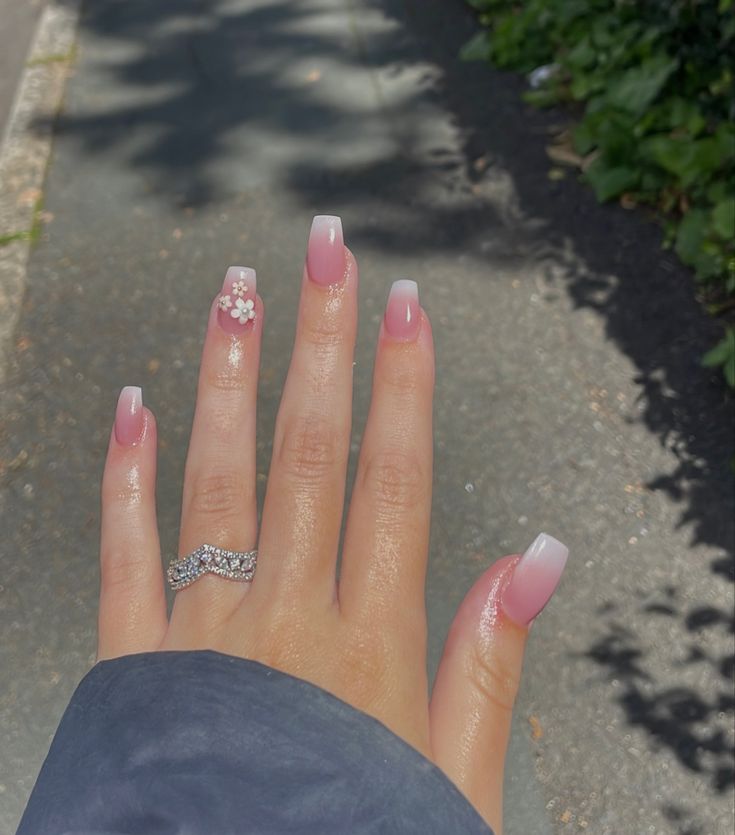 Chic Pink Ombre Nail Design with Floral Accent and Polished Finish.