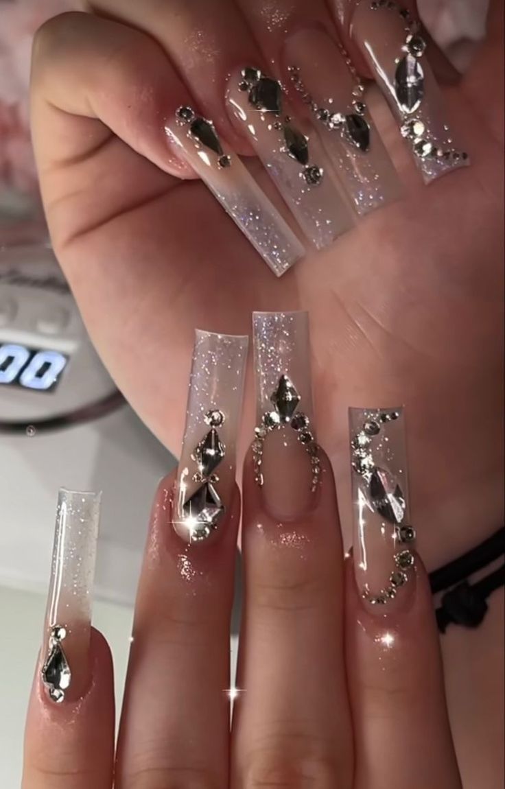 Elegant Long Clear Acrylic Nails with Metallic Embellishments and Sparkling Gradient