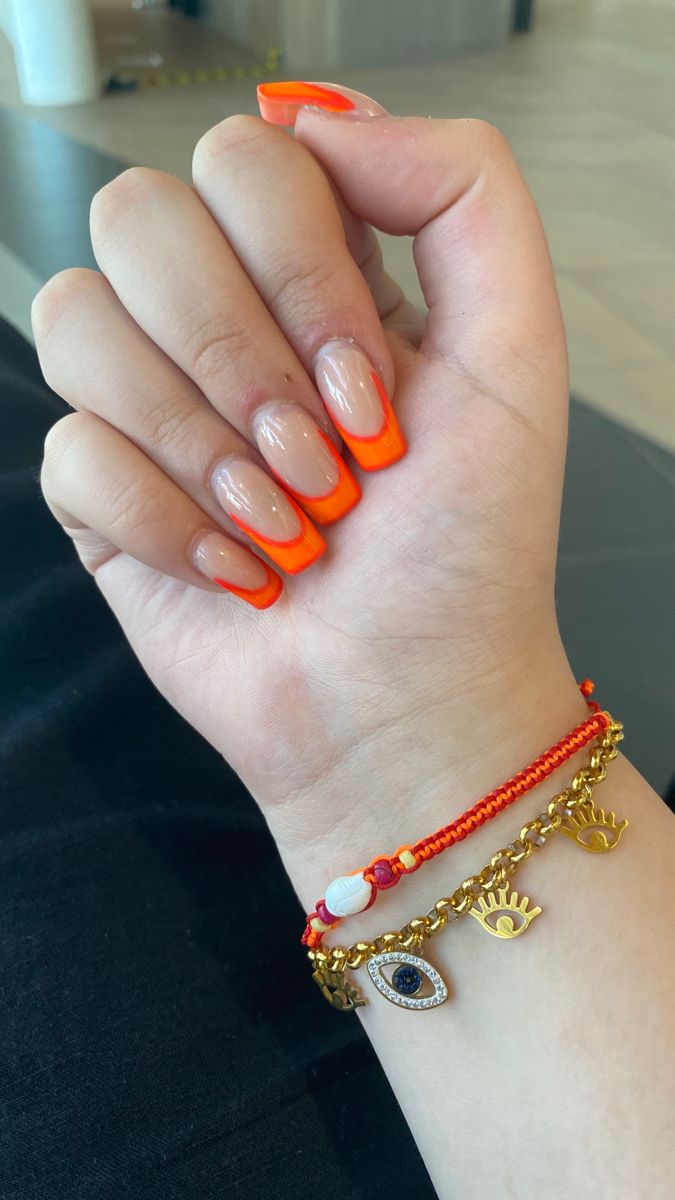 Playful Vibrant Nail Design with Bold Orange Tips and Trendy Bracelet.