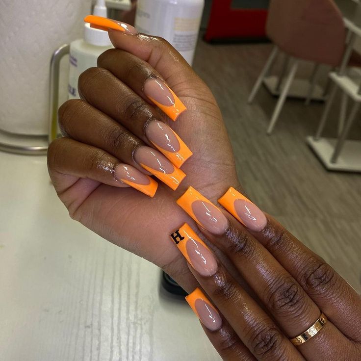 Chic Almond-Shaped Nails with Vibrant Orange French Tips and Nude Accents