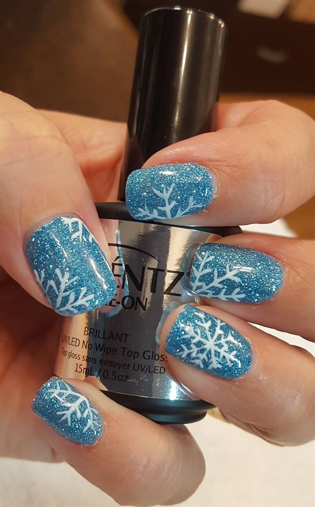 Festive Winter Wonderland: Sparkling Blue Nail Design with Delicate Snowflakes.