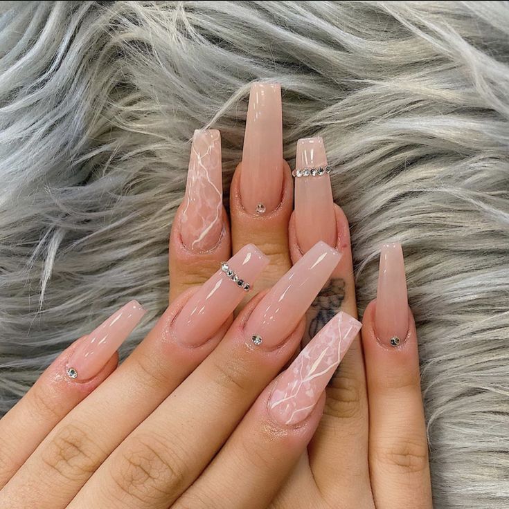 Sophisticated Long Acrylic Nails with Nude Marble Accents and Sparkling Embellishments.