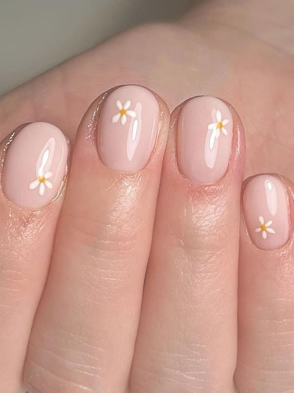 Delicate Floral Nail Art: Soft Pink with Whimsical White Daisies for Springtime Elegance.