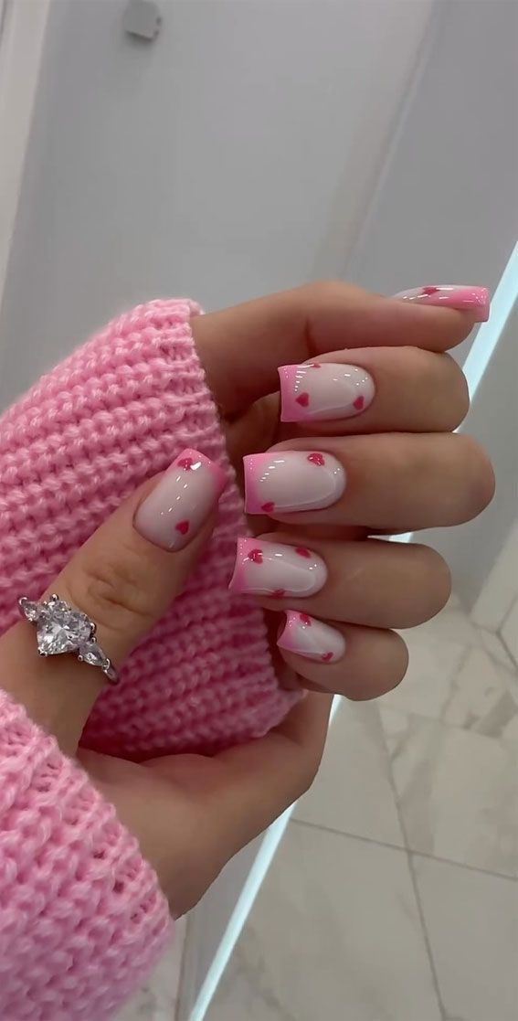 Whimsical Soft Pink Nail Design with Vibrant Tips and Heart Embellishments.