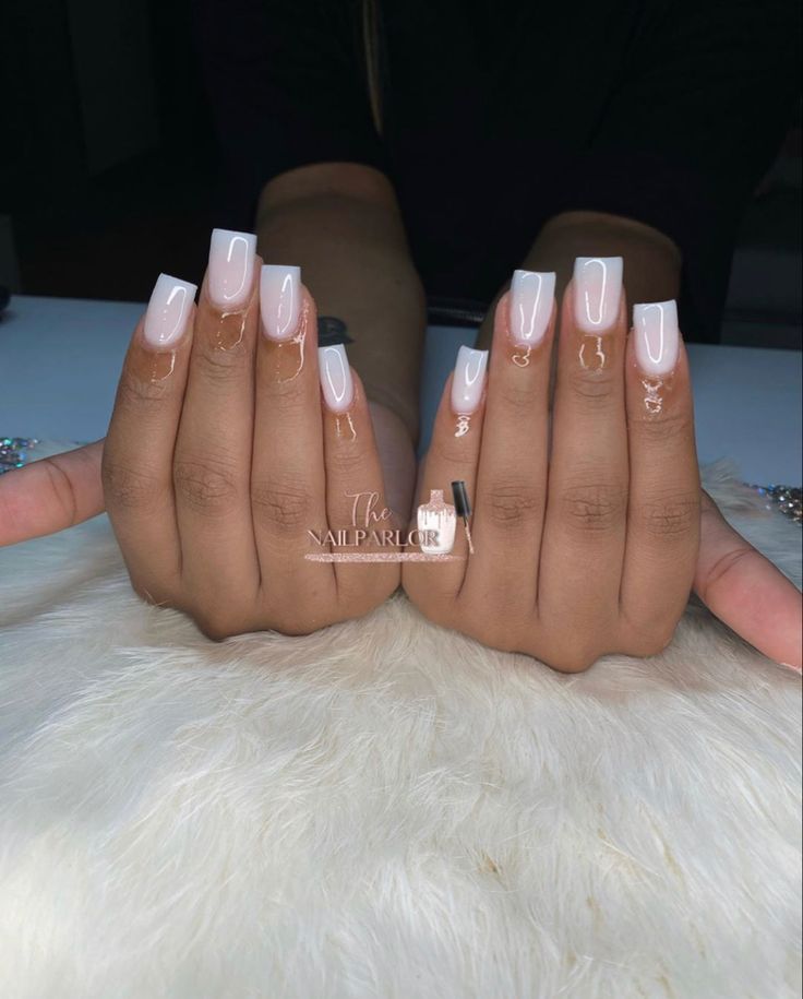 Chic Nude Base Nails with Clear Tips and Sparkling Accent Charms for a Sophisticated Look.