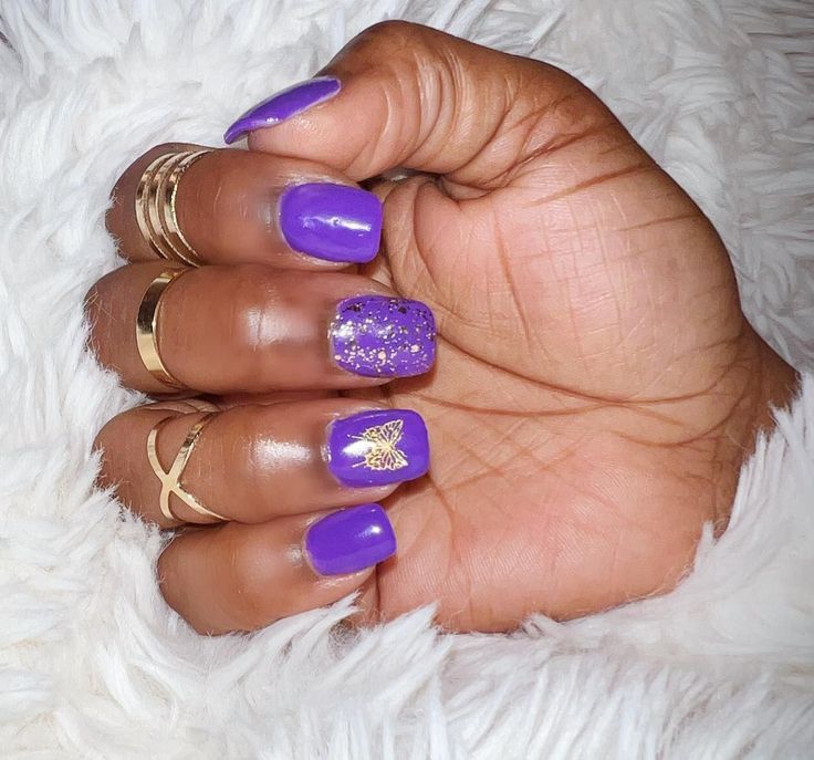 Bold Purple Manicure with Sparkling Butterfly Accent and Elegant Gold Rings.