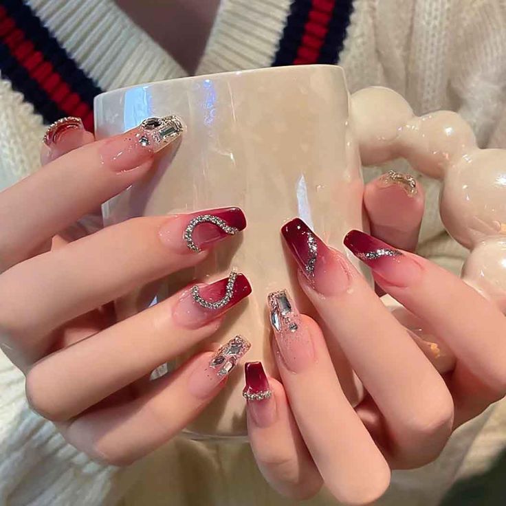 Chic Nail Design: Deep Red and Nude with Sparkling Silver Accents and Artistic Shapes.