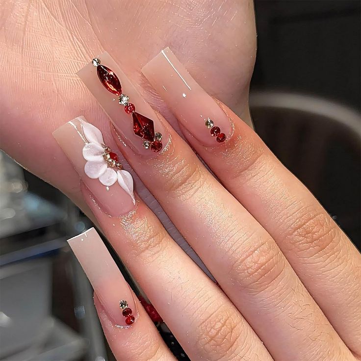 Sophisticated Floral and Gemstone Nail Design with Nude and Clear Acrylics.