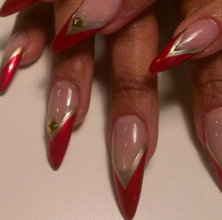 Chic Red and Gold Stiletto Nail Design with Geometric Accents and Negative Space.