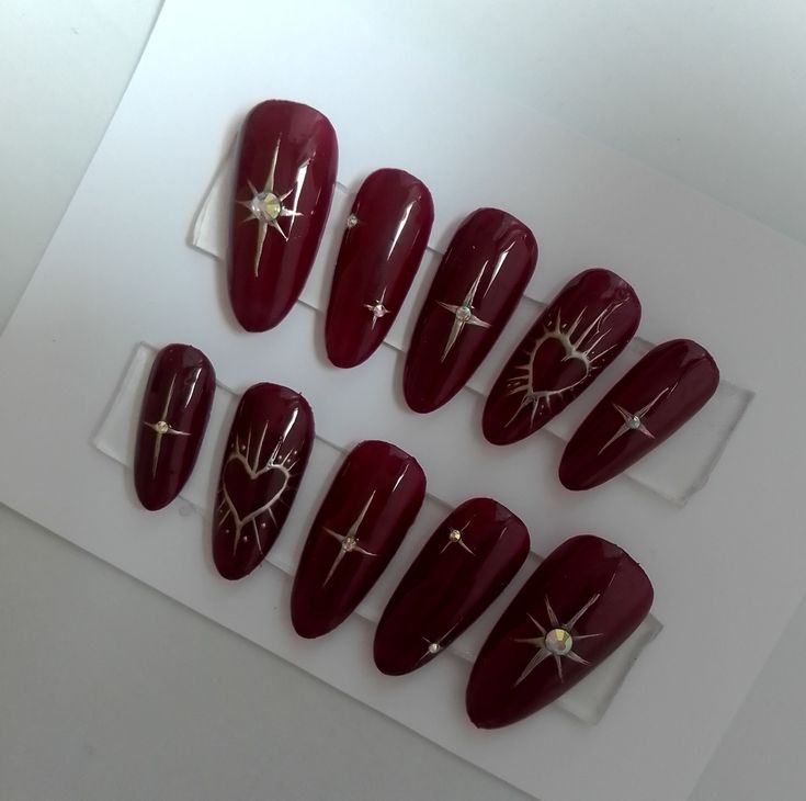 Sophisticated Burgundy Nail Design with Bold Shapes and Intricate Gold and Pearl Embellishments.