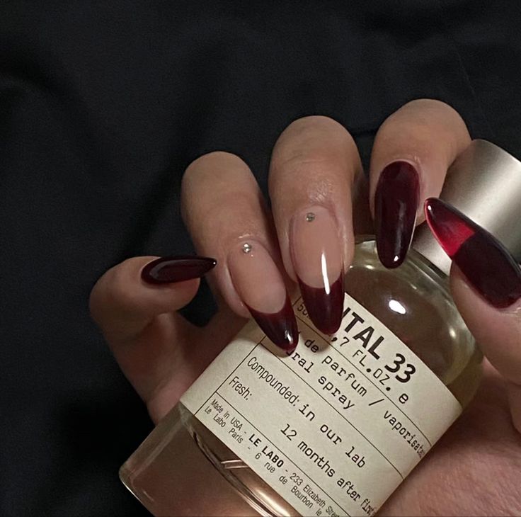 Sophisticated Deep Burgundy and Nude Nail Design with Glamorous Embellishments.