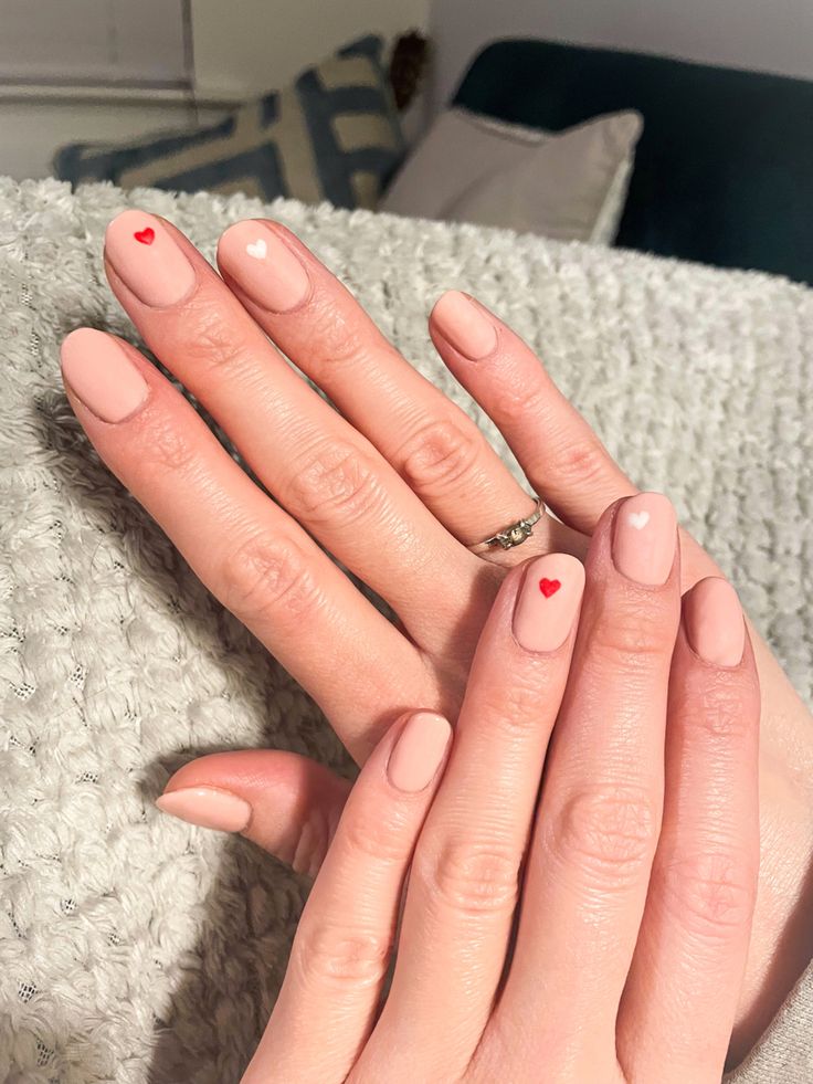 Charming Nail Design: Soft Nude Base with Playful Red and White Heart Motifs