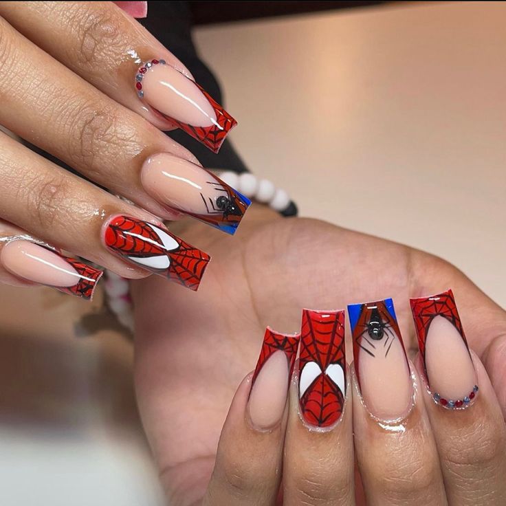 Playful Spider-Themed Nail Design: Bold Red and Black with Glamorous Rhinestones and Artistic Flair.