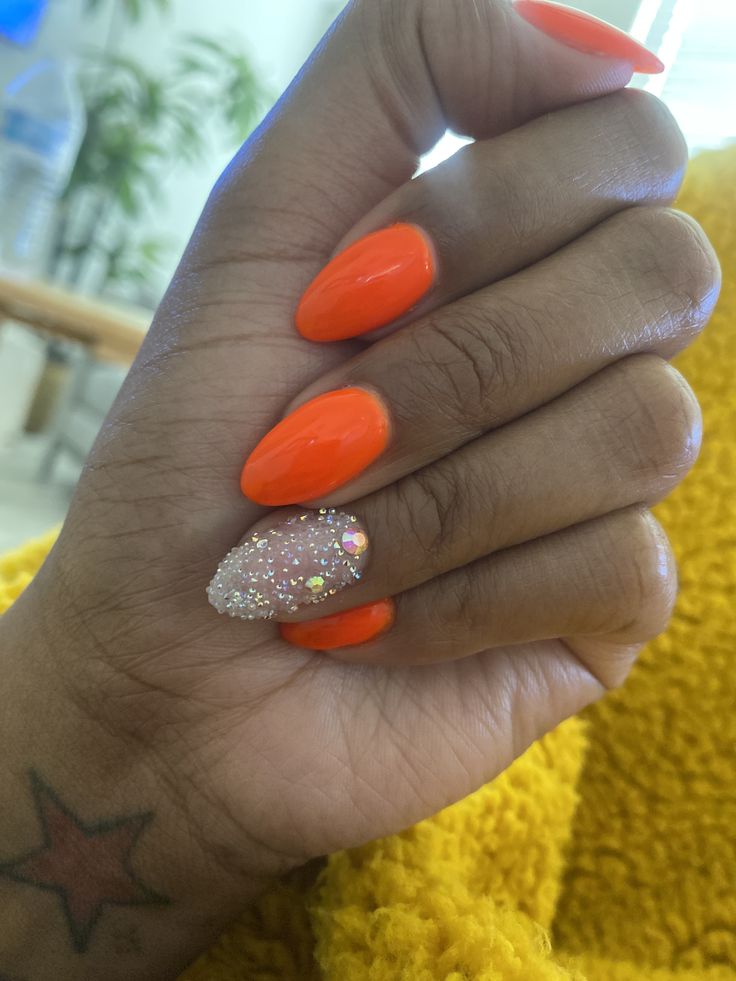 Bold and Glamorous Orange Nail Design with Glossy Finish and Glittery Accent.