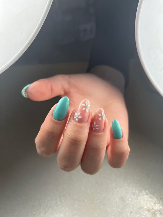 Vibrant Turquoise Nail Design with Soft Nude Base and Charming White Flower Accents.