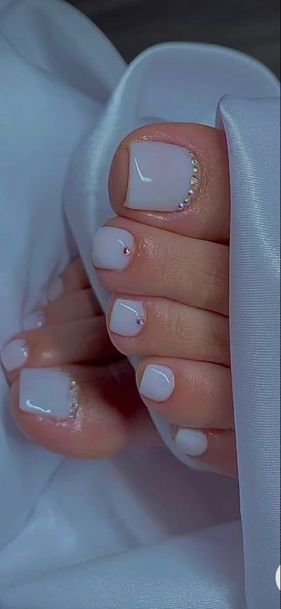 Elegant Pedicure Design: Soft White Polish with Rhinestone Accents for a Sophisticated Look