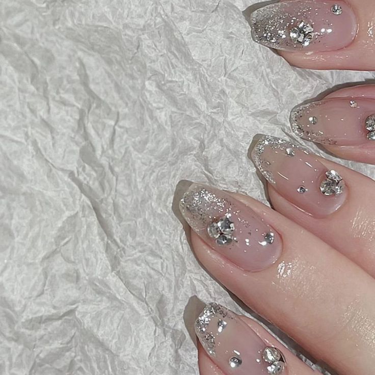 Glamorous Soft Nude Nails with Shimmering Silver Tips and Rhinestone Accents.