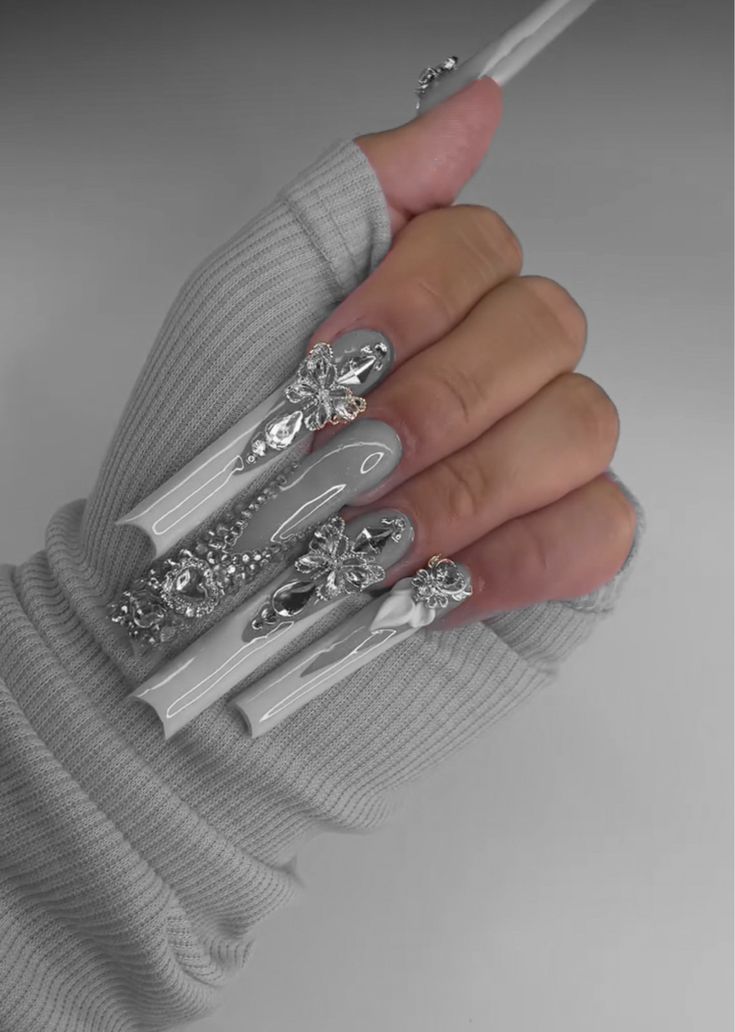 Chic Silver and White Nail Design with Glamorous Embellishments Paired with Cozy Knitted Gloves.