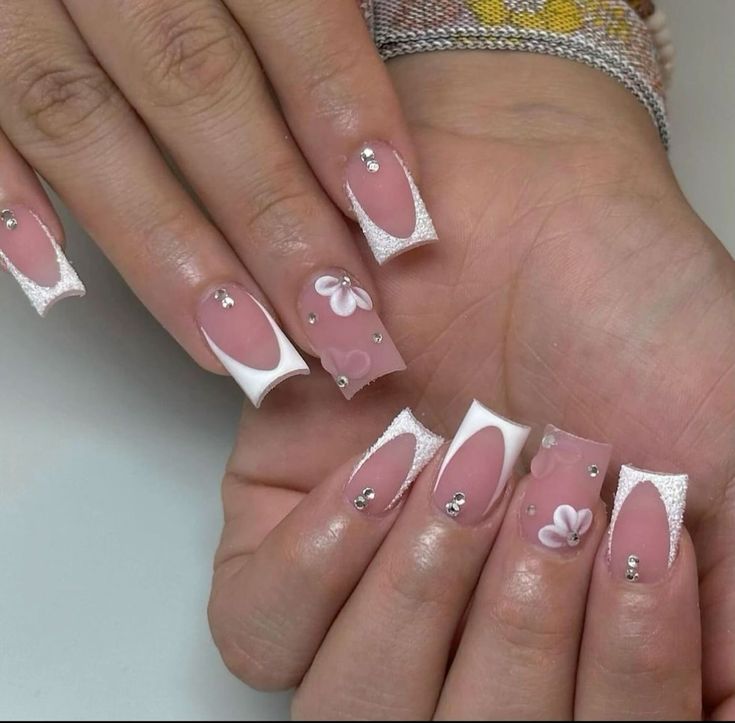 Chic Nail Art: Soft Pink and Glossy White with Intricate Floral Embellishments and Rhinestones.