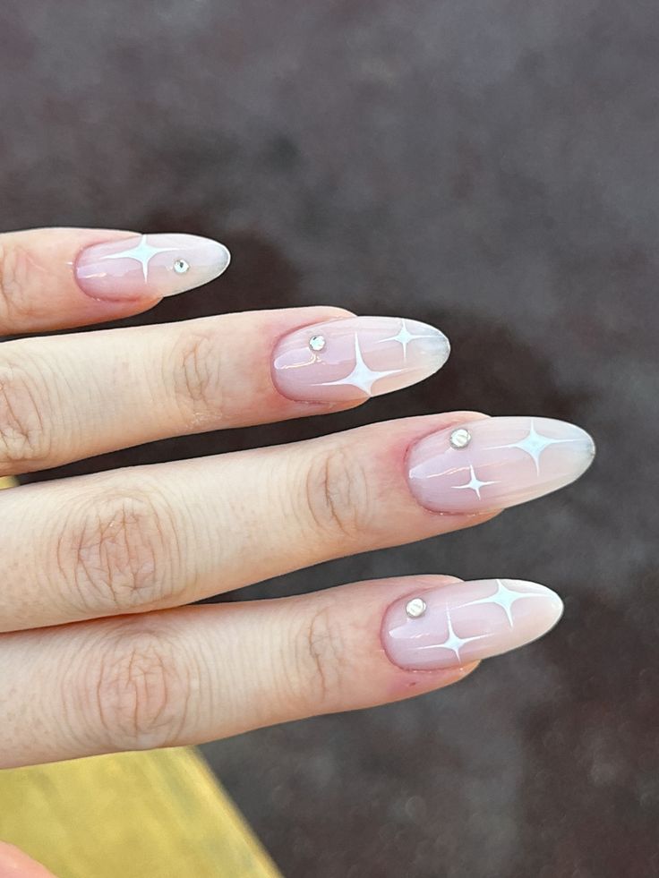 Elegant Almond-Shaped Nails with Soft Pink Gradient and Geometric White Design Accented by Rhinestones.