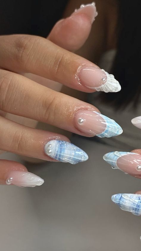 Sophisticated Ombre Nail Design with Delicate Blue Patterns and Glossy Pearl Accents.