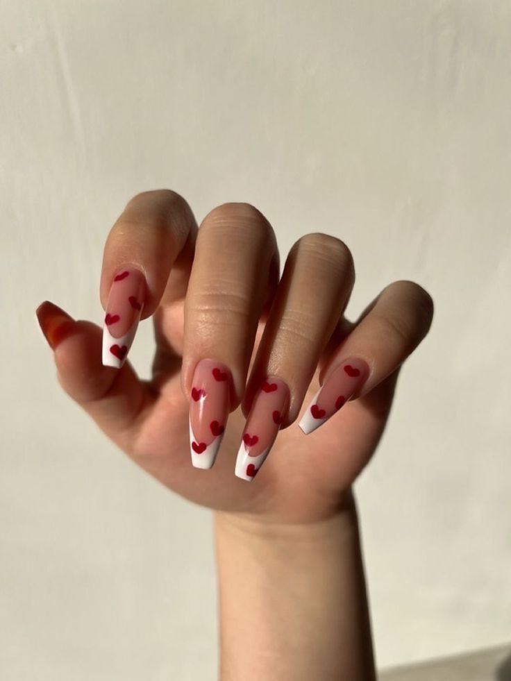 Romantic Heart-Inspired Nail Art: Almond-Shaped Design with Playful White Tips and Vibrant Red Hearts.